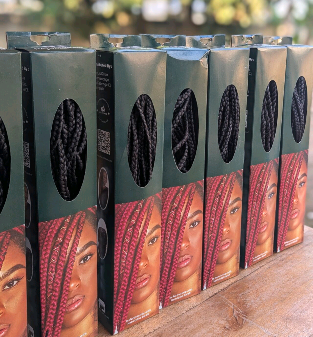 [color:Black] Several boxes of black braided hair extensions arranged in a row on a wooden surface, with oval cutouts showing the black braids inside and printed model photos on the front.